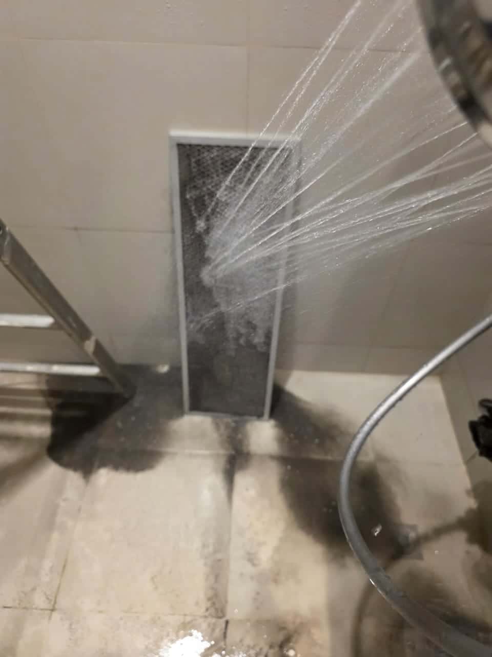 Technician clearing plumbing drain and AC discharge pipe